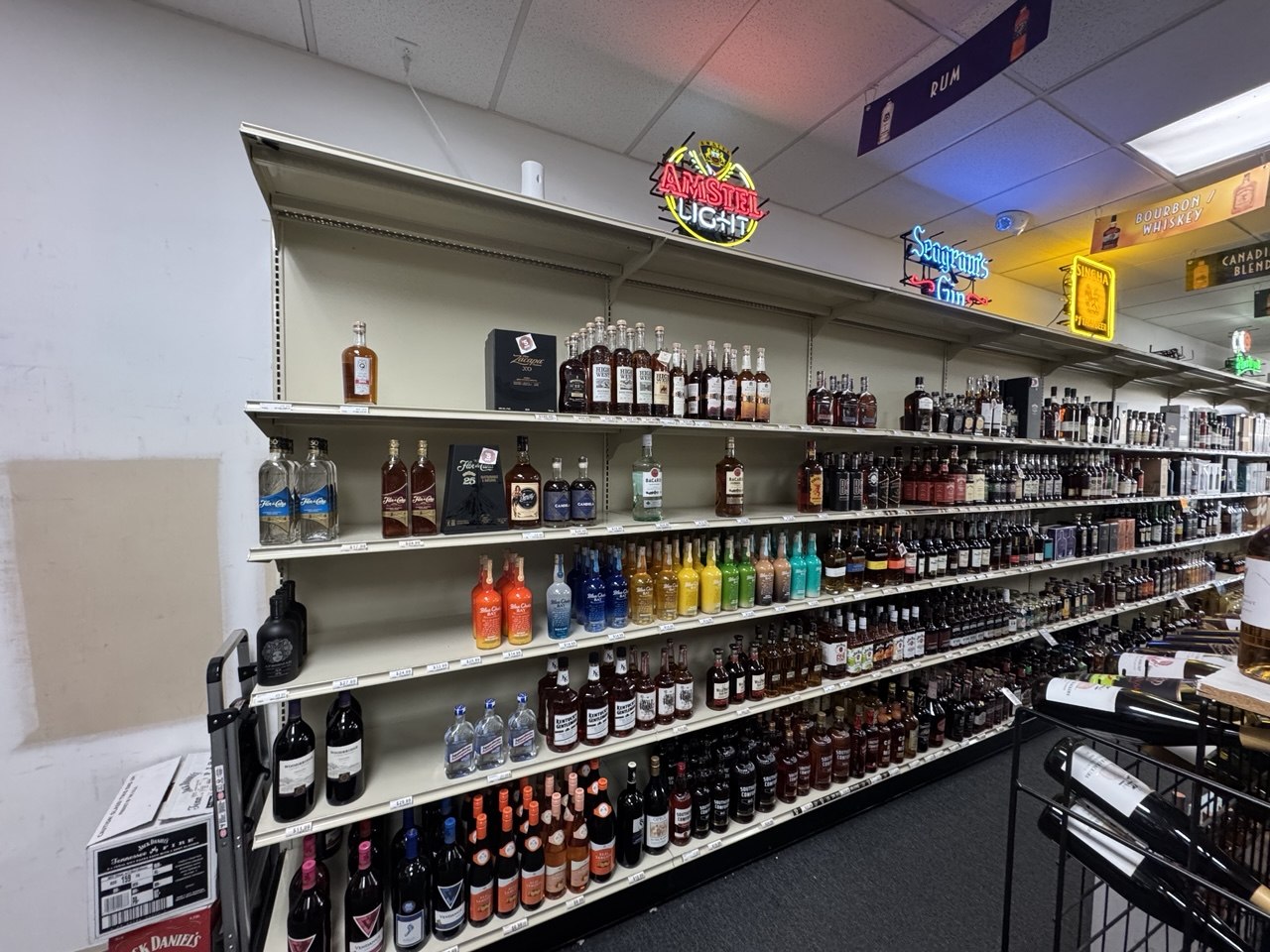 Long liquor store shelving run with mixed bottle inventory